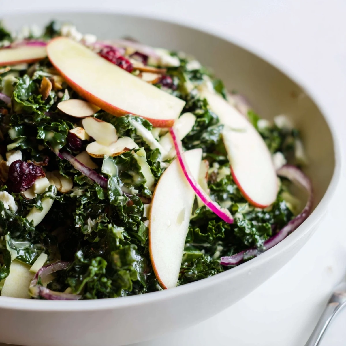 Bright Shaved Kale Apple Almond Salad Bowl with Maple Dressing, massaged kale and feta.