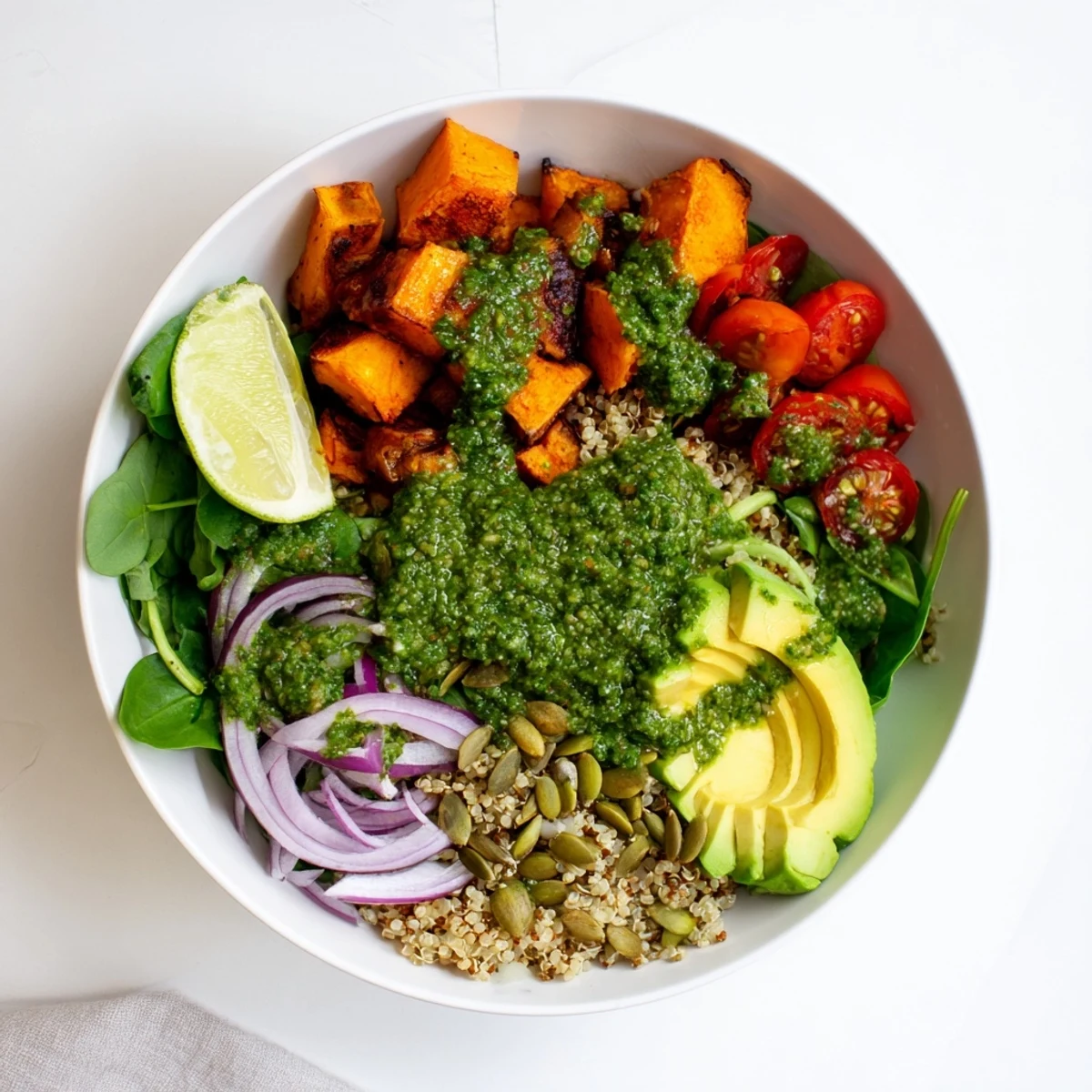 Colorful roasted sweet potato chimichurri quinoa grain bowl topped with creamy avocado and crunchy pumpkin seeds