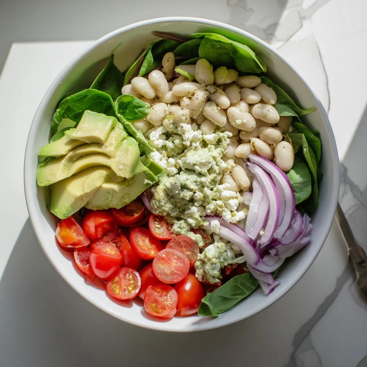 Mediterranean-inspired creamy avocado basil white bean salad served in rustic bowl with cherry tomatoes