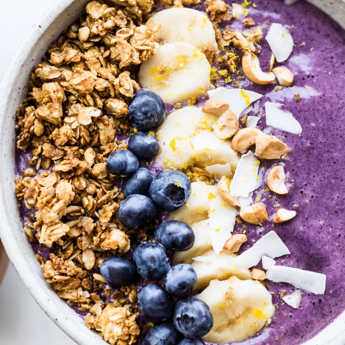 Zesty blueberry lemon cashew breakfast bowl layered with toasted oat granola and colorful fruit toppings