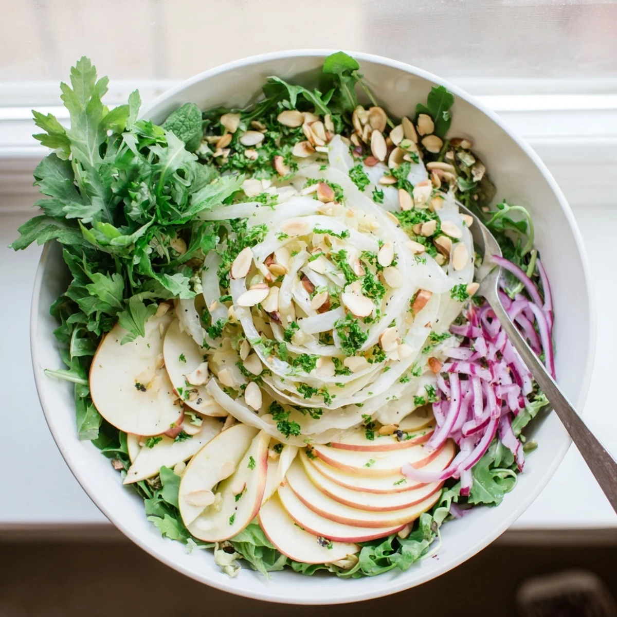 Crisp shaved fennel and apple salad bowl served with tangy citrus vinaigrette and toasted almonds