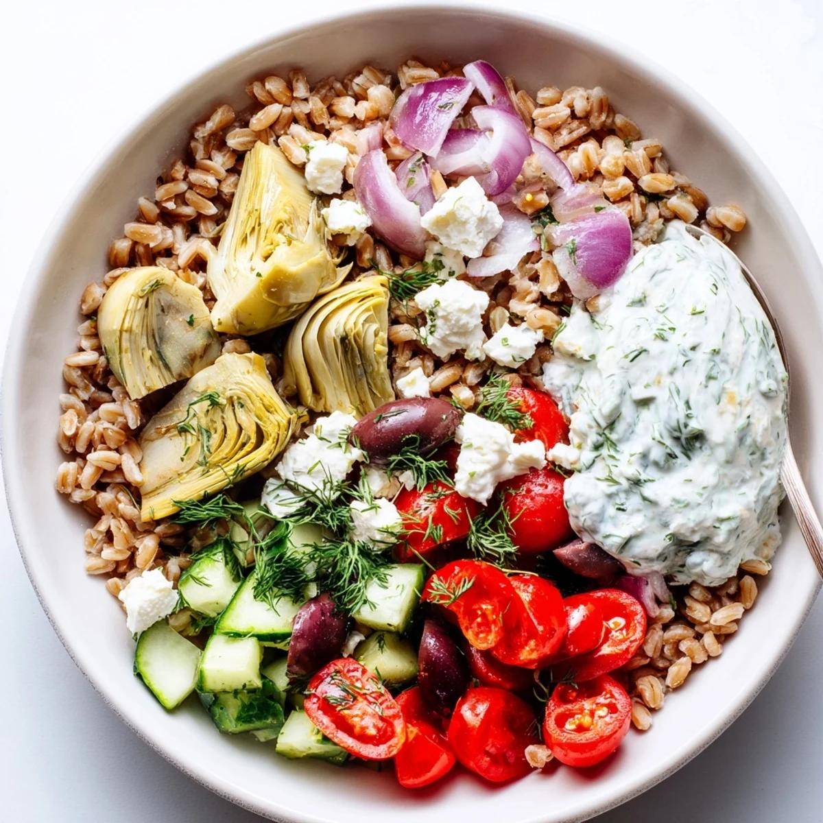 Vibrant vegetarian farro bowl featuring roasted artichokes, crisp vegetables, and tangy herb yogurt sauce