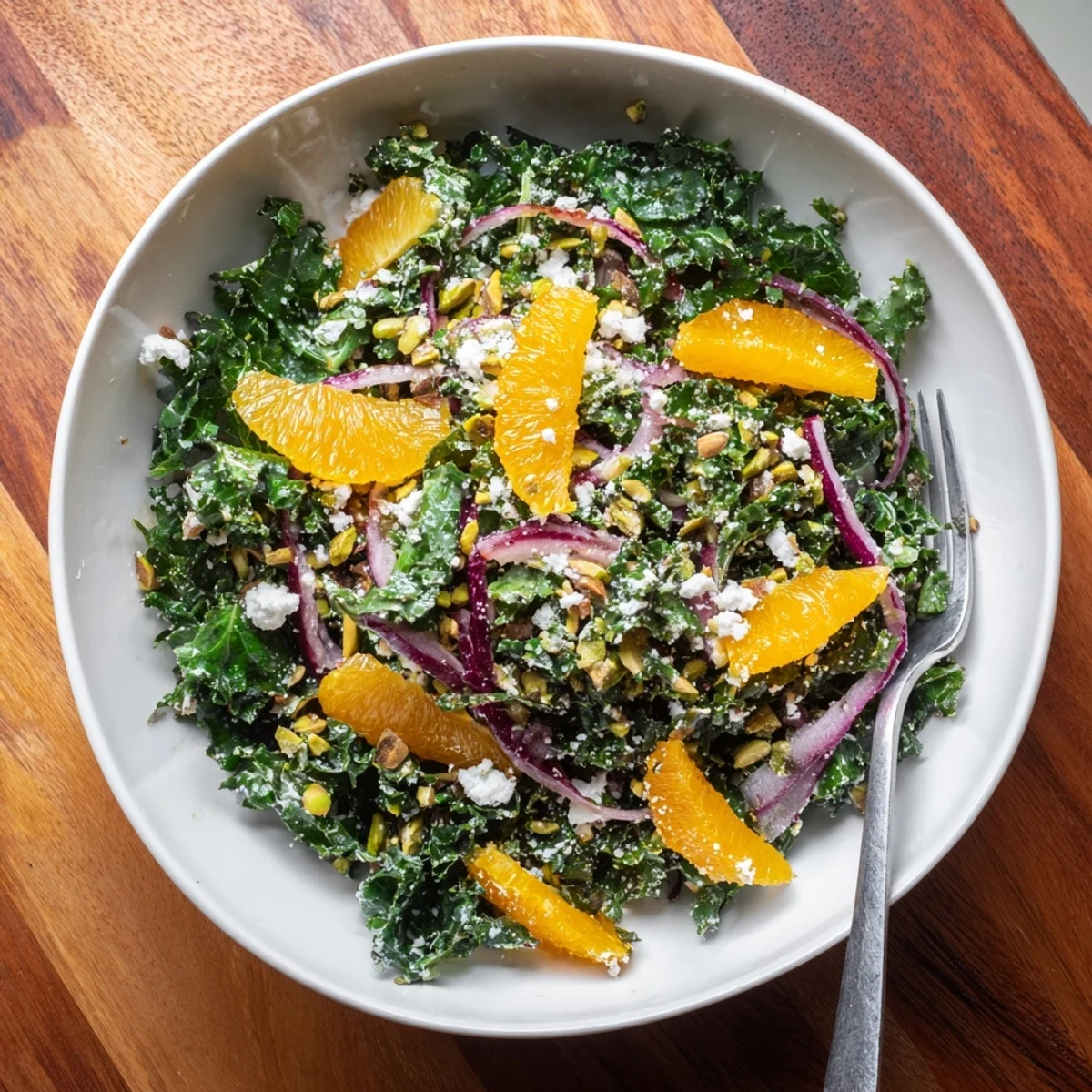 Colorful salad bowl with tender massaged kale oranges roasted pistachios and zesty citrus vinaigrette