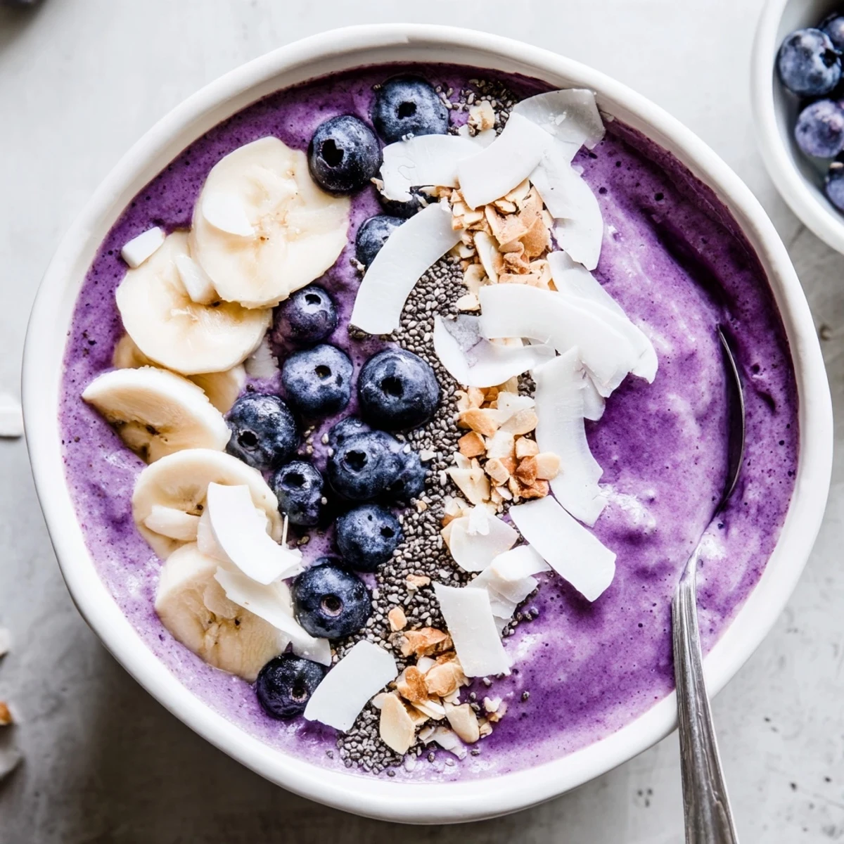Creamy blueberry banana almond smoothie bowl with colorful toppings served in a white bowl