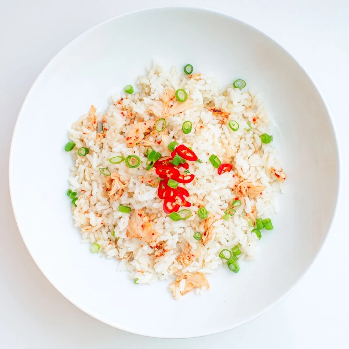 Golden kimchi garlic chili fried rice scattered with vibrant scallion greens in a bowl