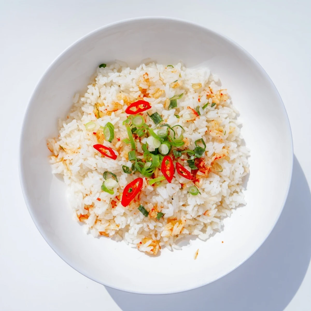 Steaming plate of spicy kimchi fried rice topped with fresh scallions and aromatic garlic