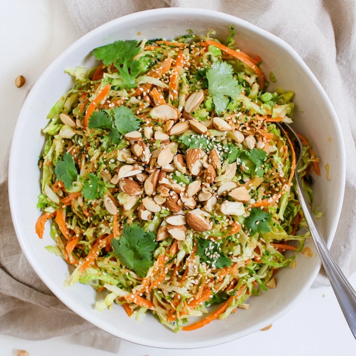 Fresh cabbage carrot almond salad bowl with golden toasted sesame seeds and tangy dressing, perfect as a light vegetarian side dish
