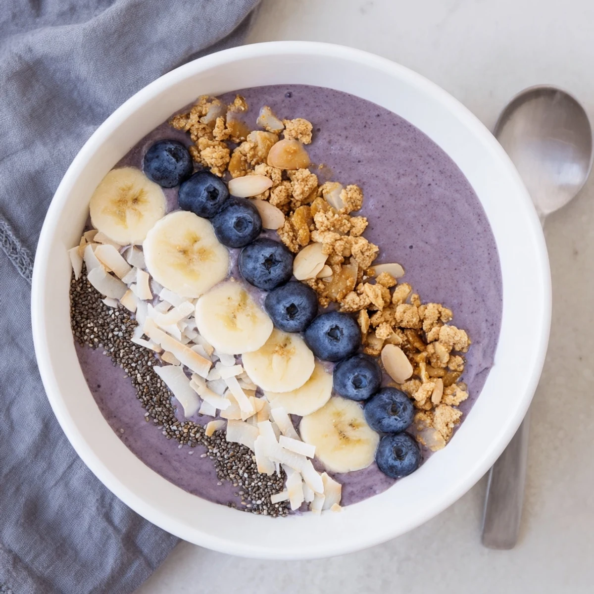 Creamy breakfast parfait of Blueberry Almond Coconut Smoothie Bowl with Granola Clusters