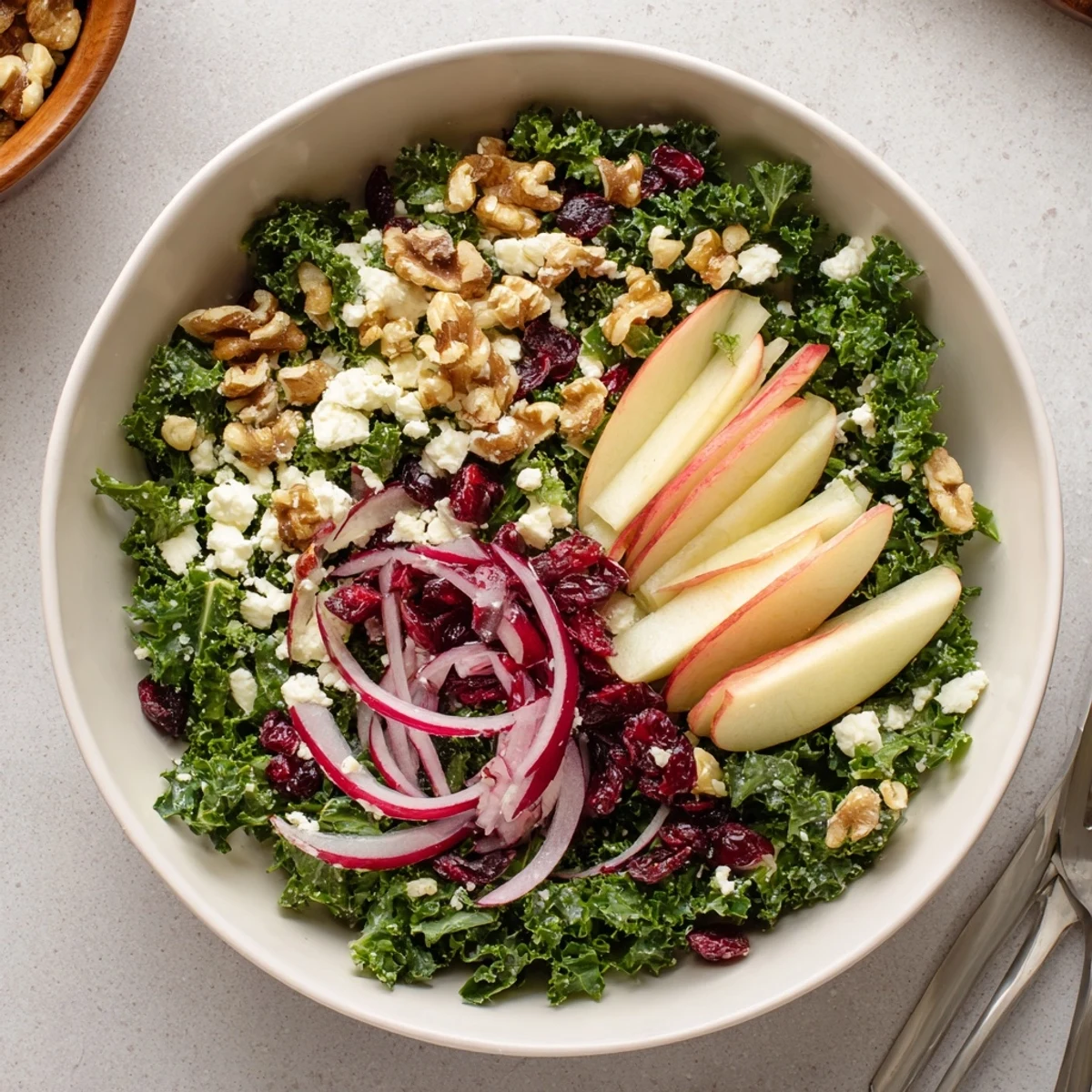 Toasted walnuts crown a Shaved Kale Apple Walnut Salad Bowl with Maple Dressing.