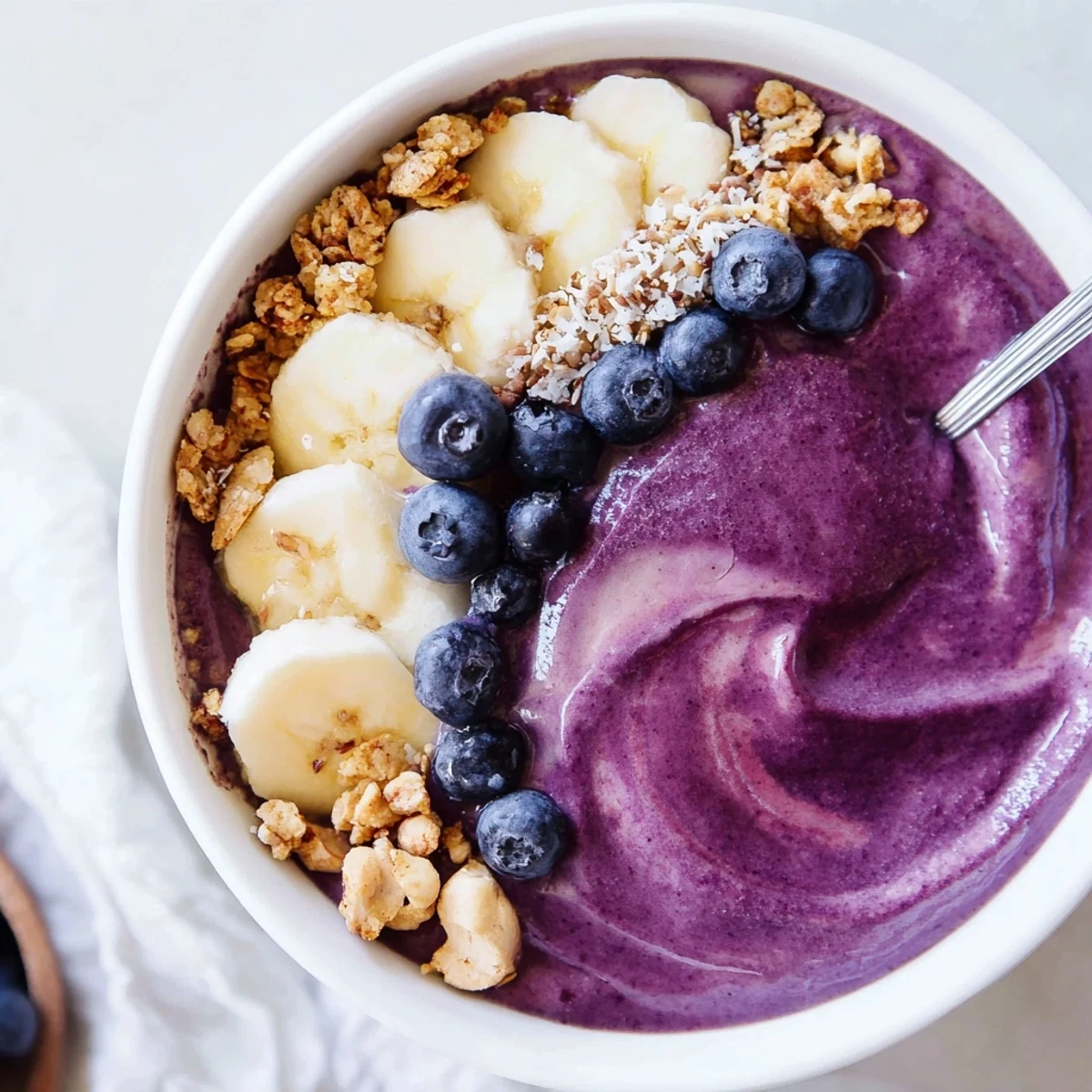 Blueberry Banana Cashew Smoothie Bowl with Granola Crumble, creamy purple base with crunchy granola.