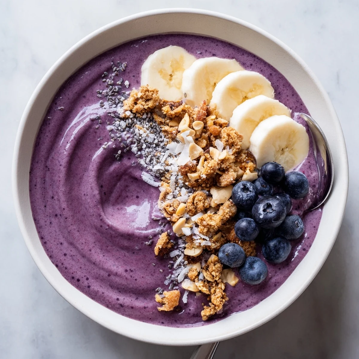 Bright Blueberry Banana Cashew Smoothie Bowl with Granola Crumble, silky, topped with fresh fruit.