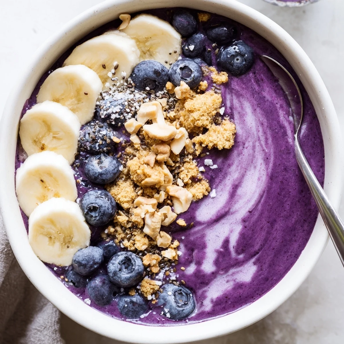Blueberry Banana Cashew Smoothie Bowl with Granola Crumble served with spoon, ideal quick breakfast.
