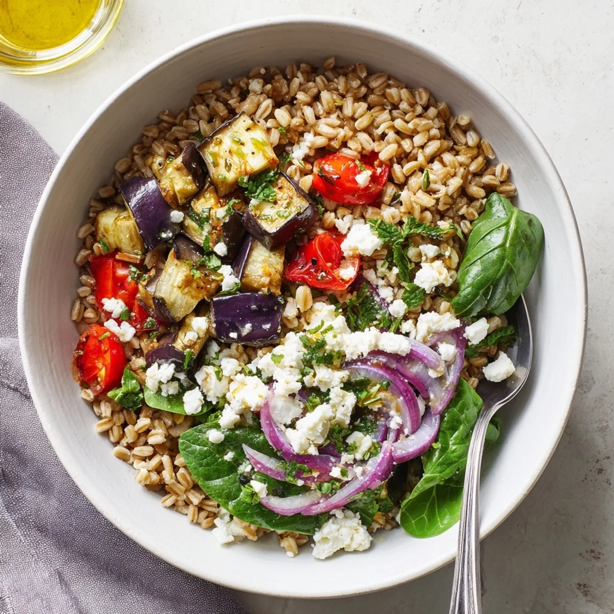 Mediterranean roasted eggplant farro grain bowl featuring tender roasted vegetables, fresh spinach, and zesty lemon-oregano dressing