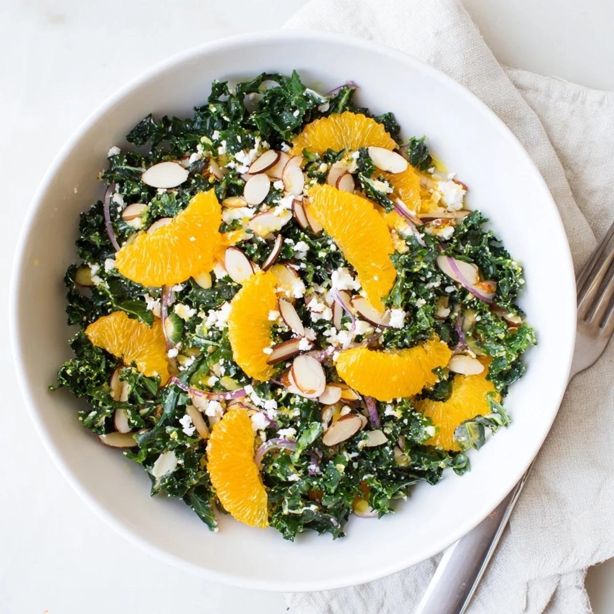 Colorful shaved kale orange almond salad bowl with citrus dressing and bright orange segments