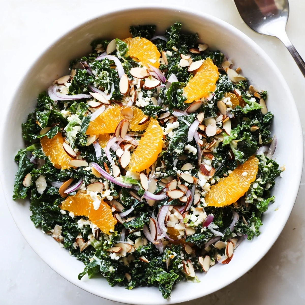 Vibrant shaved kale orange almond salad bowl featuring juicy oranges and crunchy toasted almonds
