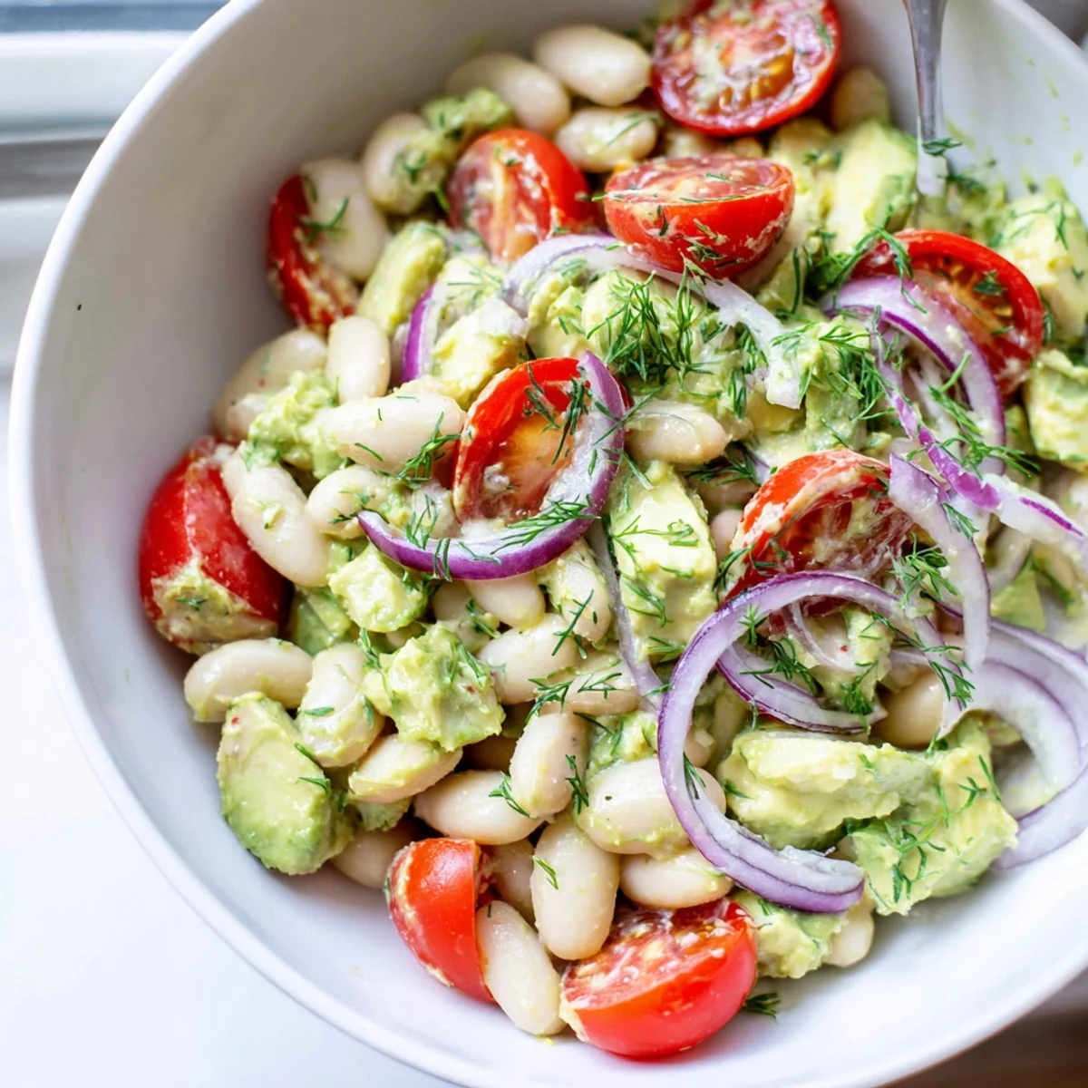 Creamy avocado lemon white bean salad bowl with fresh dill dressing and toasted pumpkin seed garnish