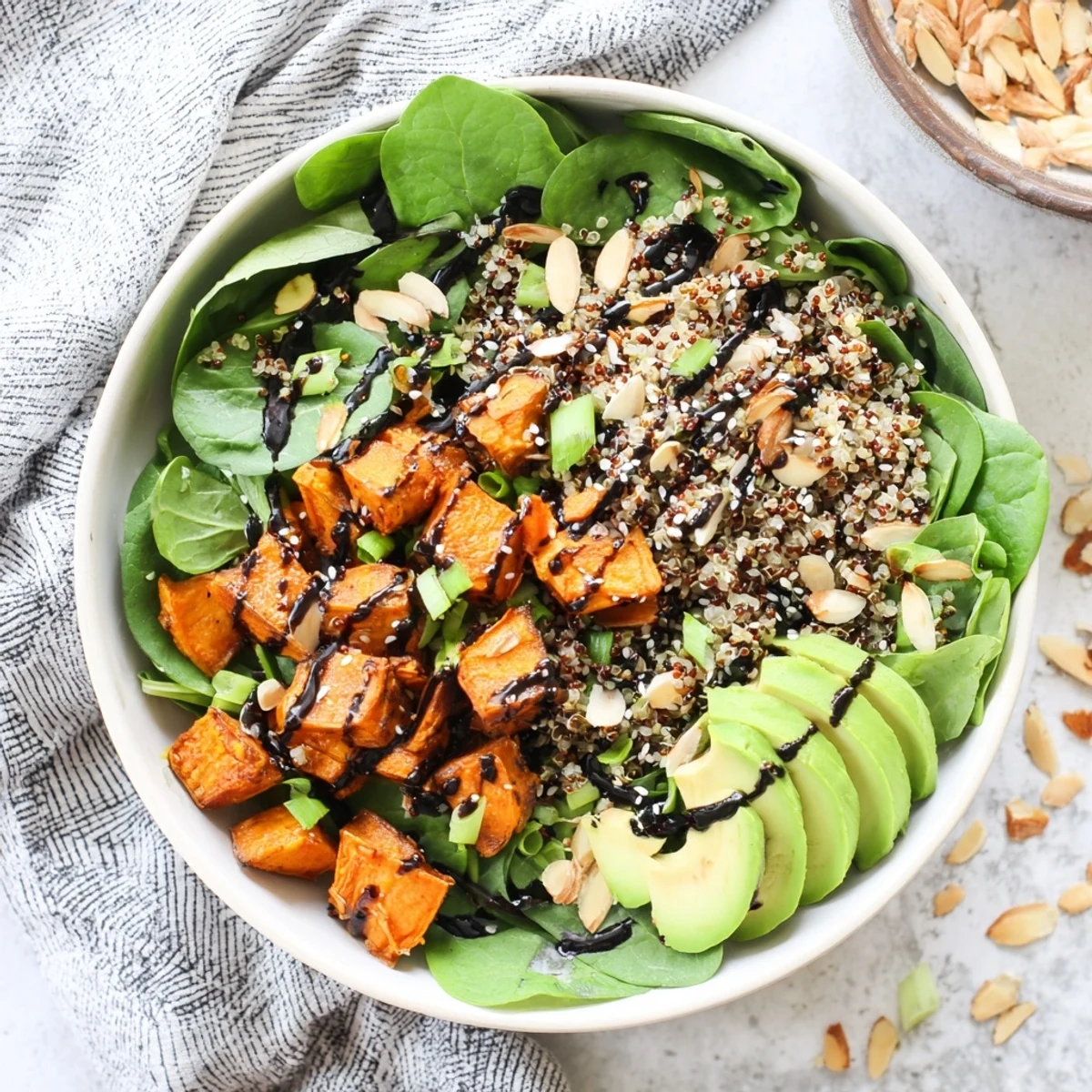 Golden roasted sweet potato black garlic quinoa grain bowl with sesame crunch topping