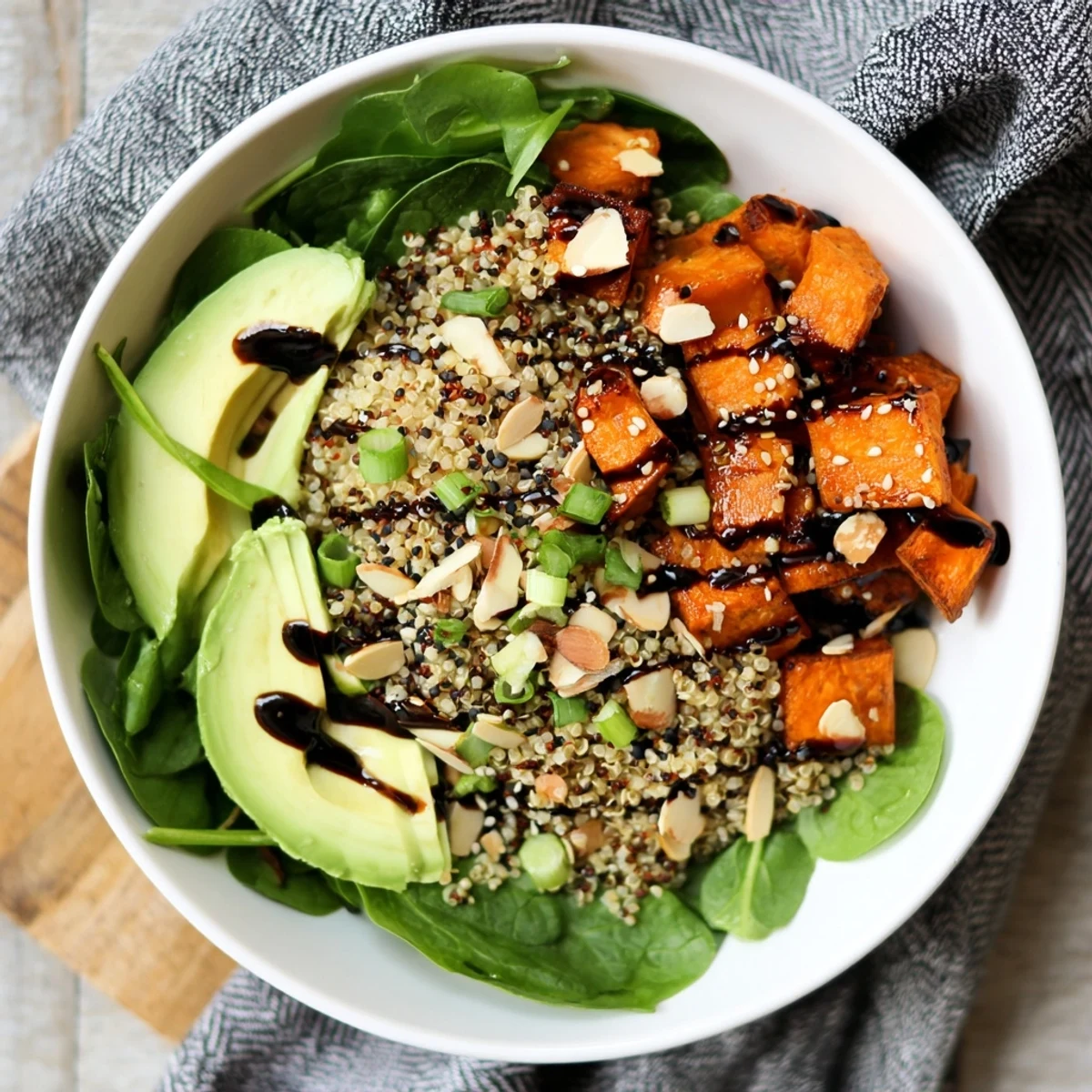 Vibrant vegetarian grain bowl featuring roasted sweet potatoes with black garlic and sesame seeds