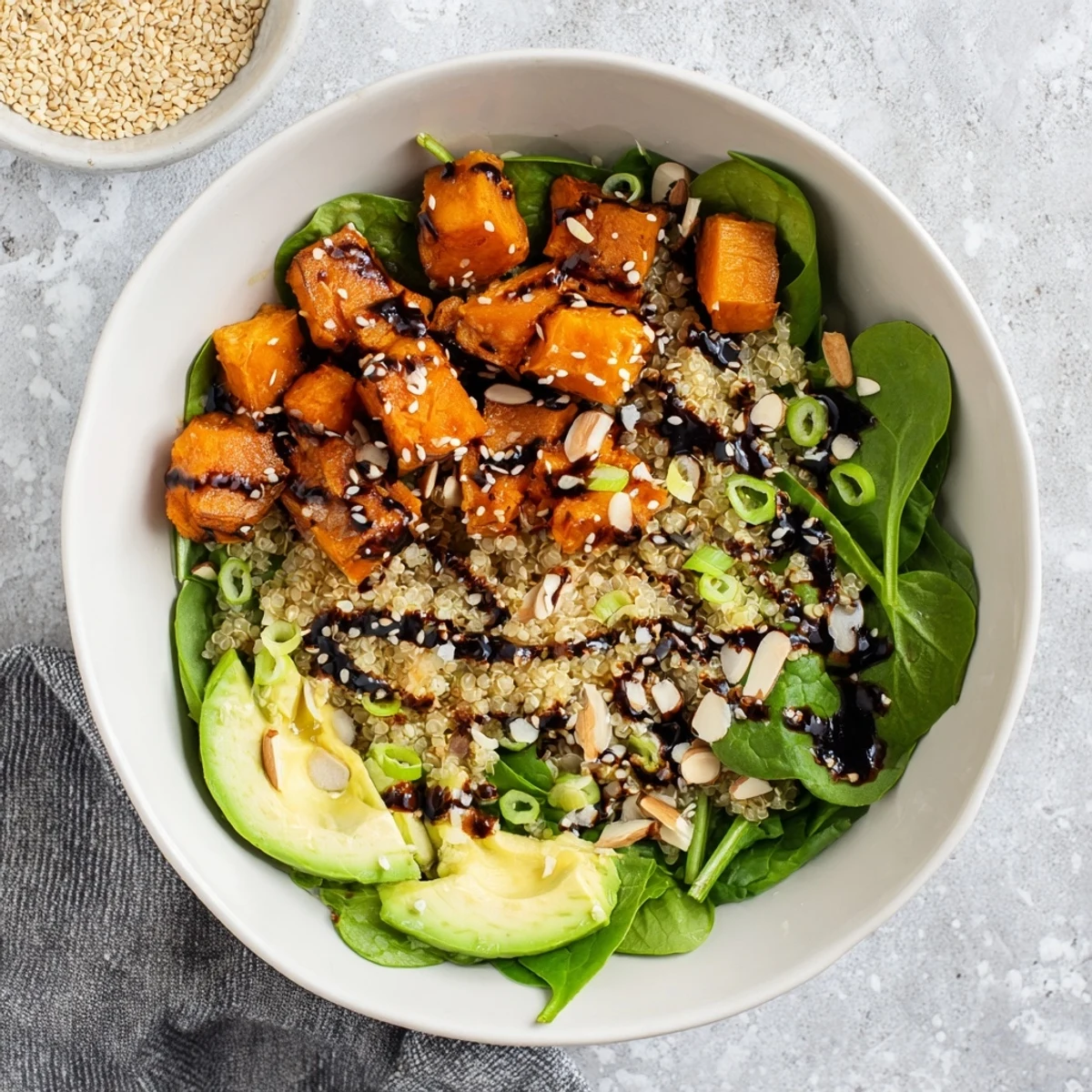 Fluffy quinoa bowl topped with caramelized sweet potatoes and savory black garlic dressing