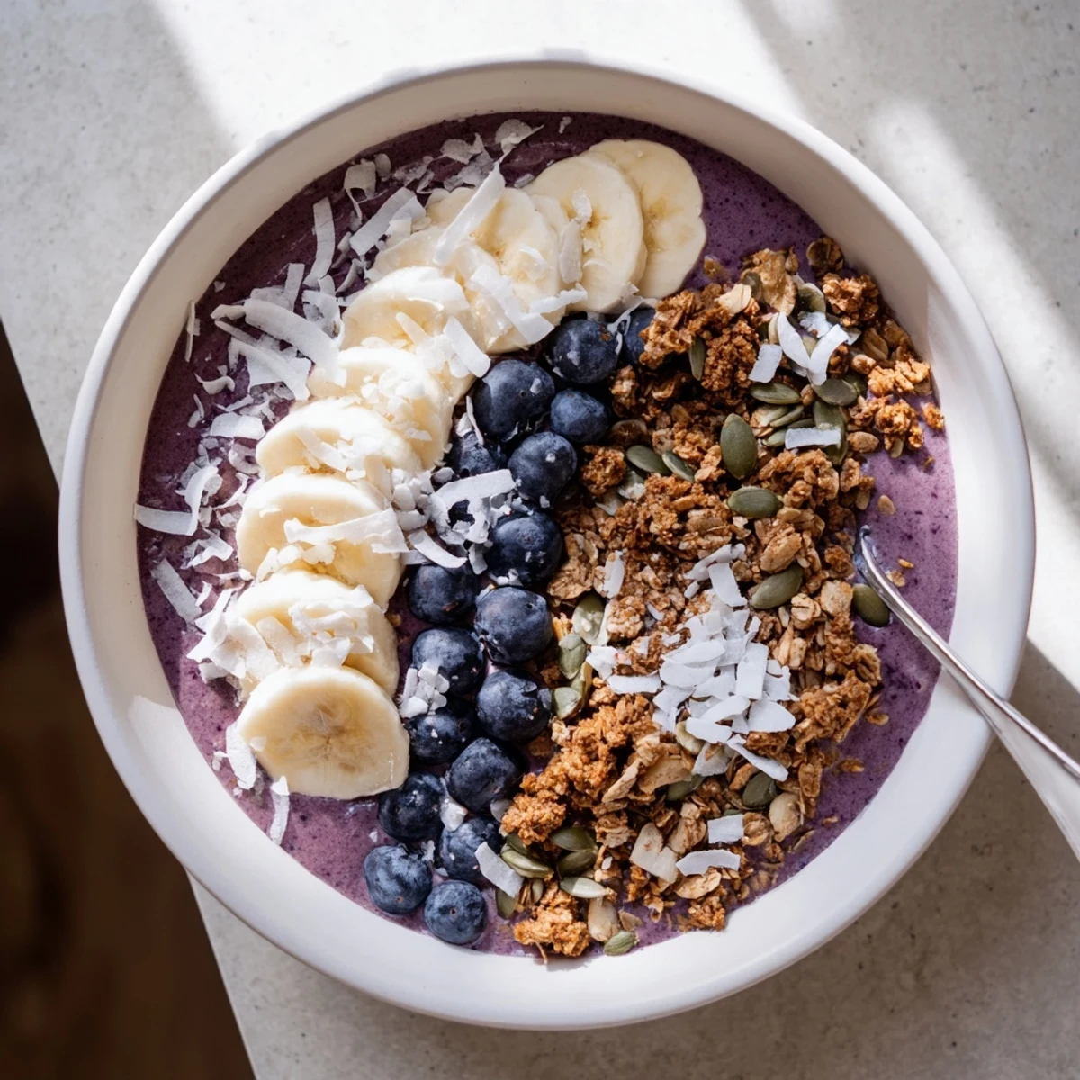 Vibrant smoothie bowl layered with frozen blueberries banana coconut milk and crispy granola