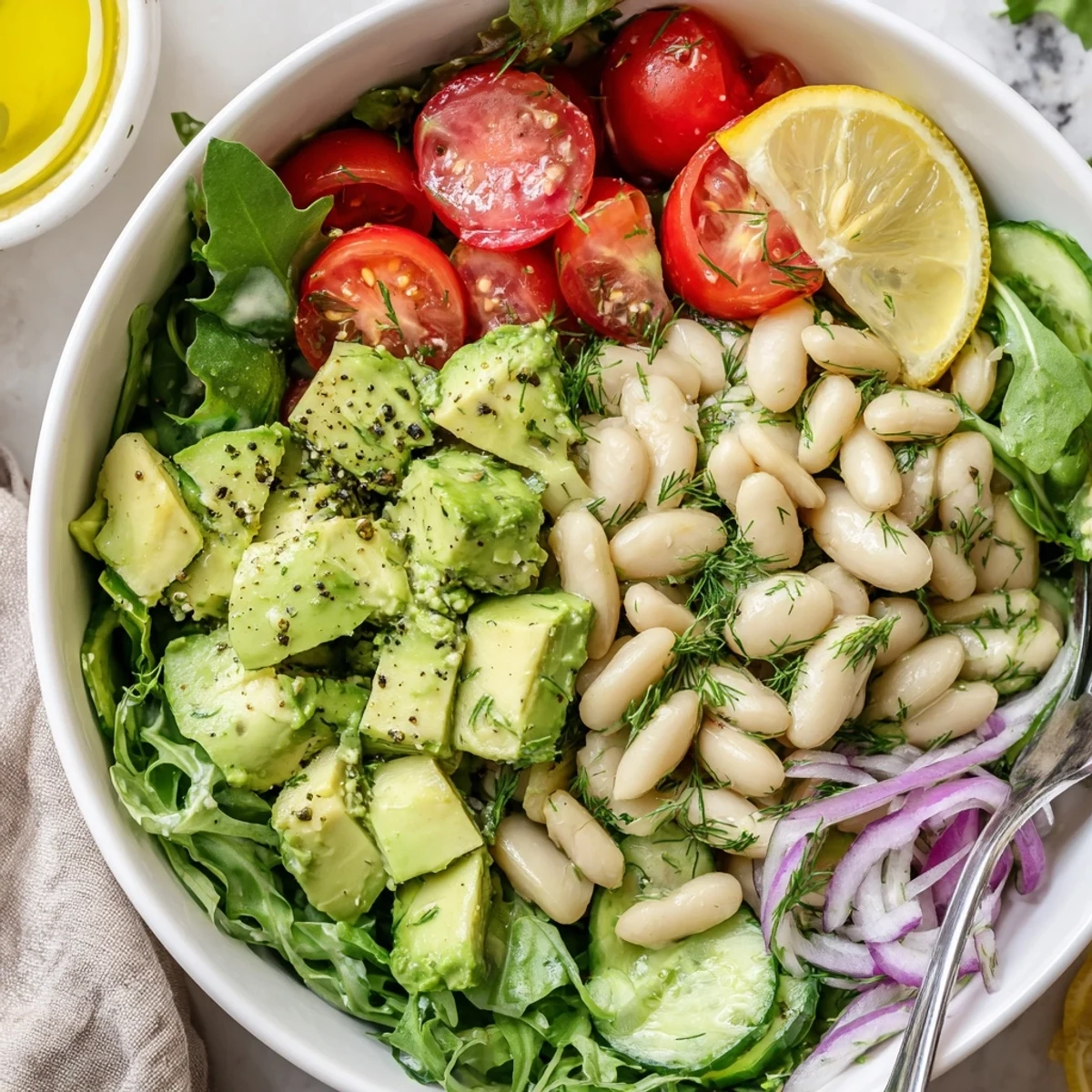 Creamy Avocado Dill White Bean Salad Bowl with Lemon plated with arugula, juicy tomatoes.