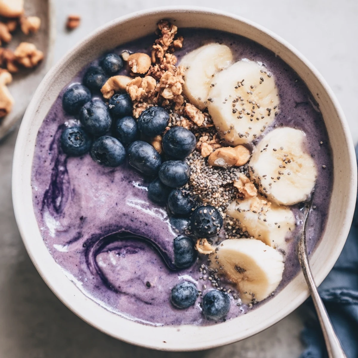Creamy Blueberry Banana Cashew Smoothie Bowl with Granola Clusters topped with sliced banana
