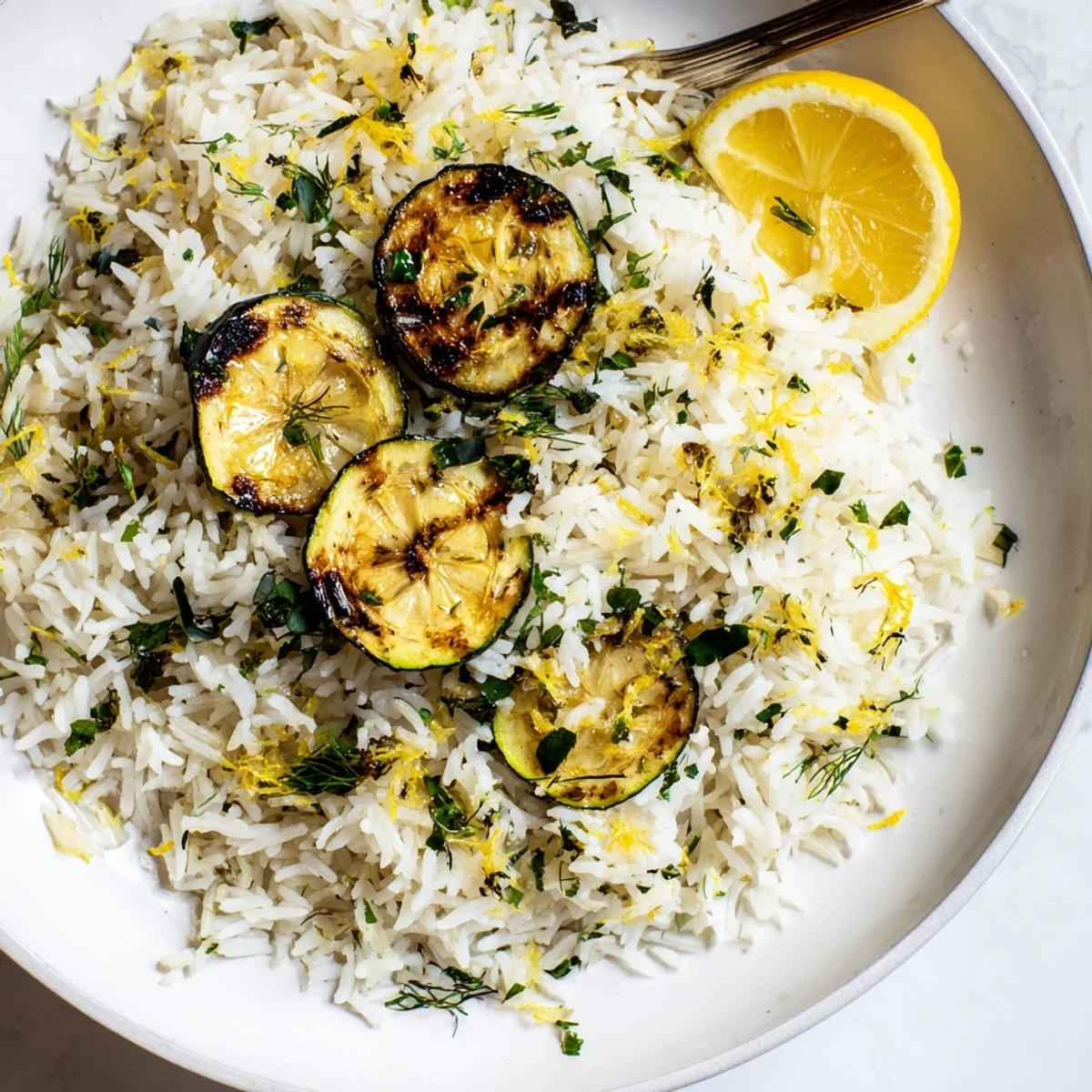 Warm plate featuring Garlic Lemon Herb Jasmine Rice with Charred Zucchini and lemon wedges