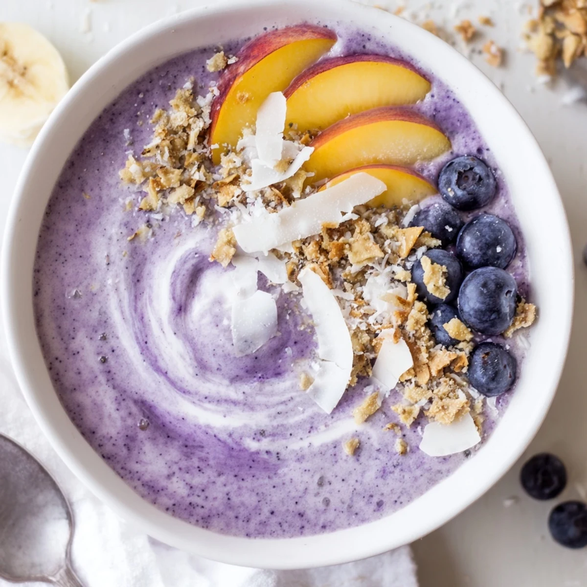 Single serving Blueberry Peach Coconut Smoothie Bowl with Almond Crumble, silky, fruity layers