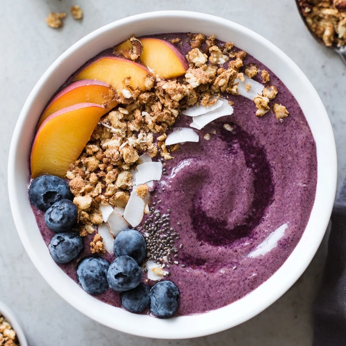 Blueberry Peach Coconut Smoothie Bowl with Almond Crumble, chilled, topped with fresh peaches