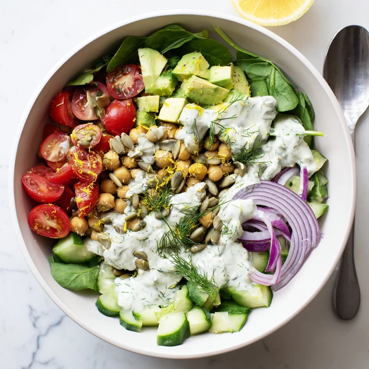 Protein-packed creamy avocado dill chickpea salad served in a white bowl with fresh vegetables