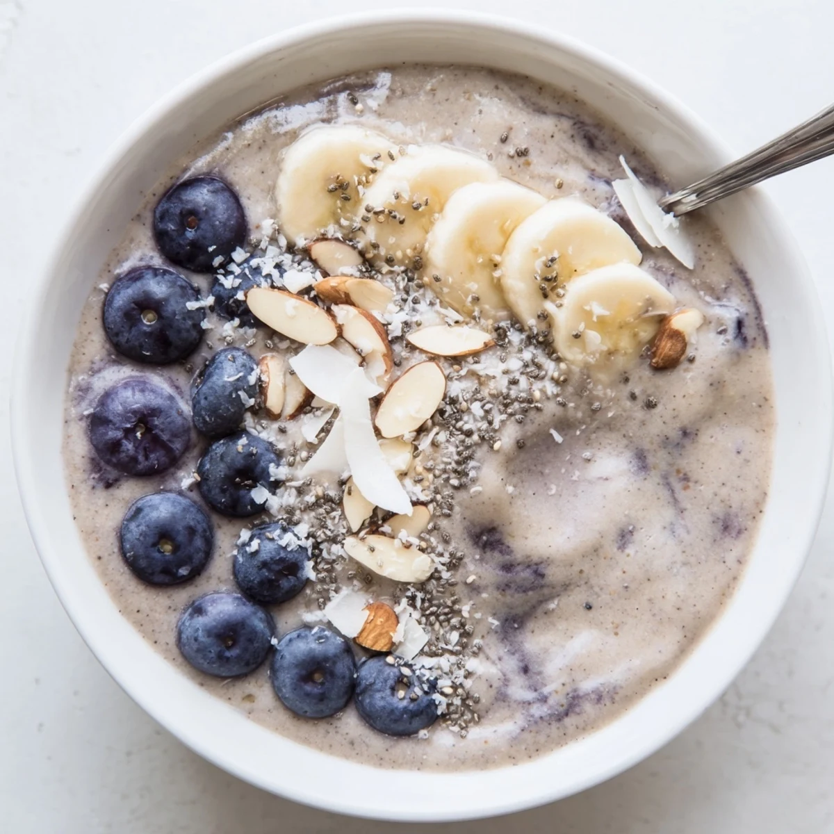 Bright, icy Blueberry Banana Almond Smoothie Bowl with Coconut Flakes served for breakfast