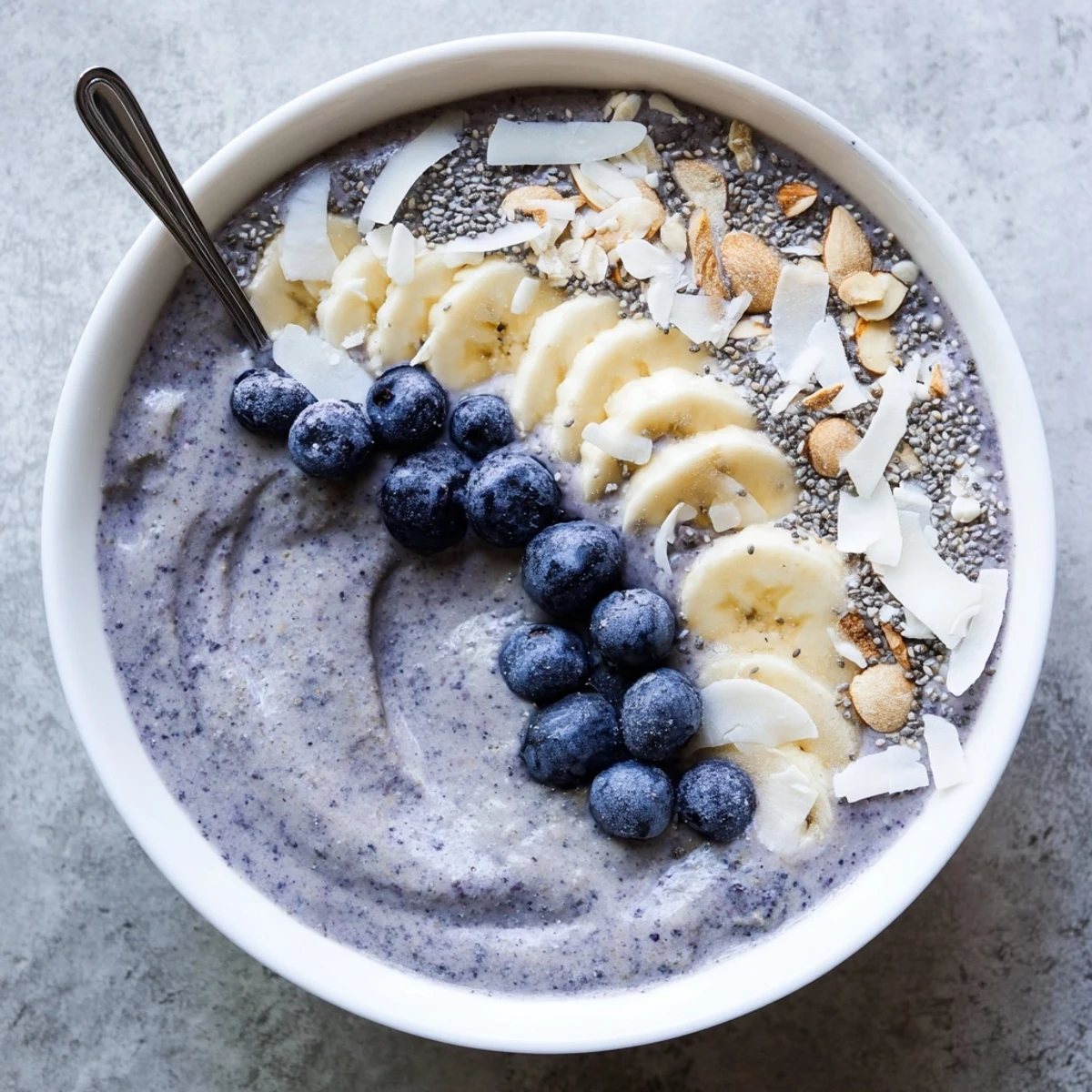 Creamy Blueberry Banana Almond Smoothie Bowl with Coconut Flakes, topped with sliced almonds