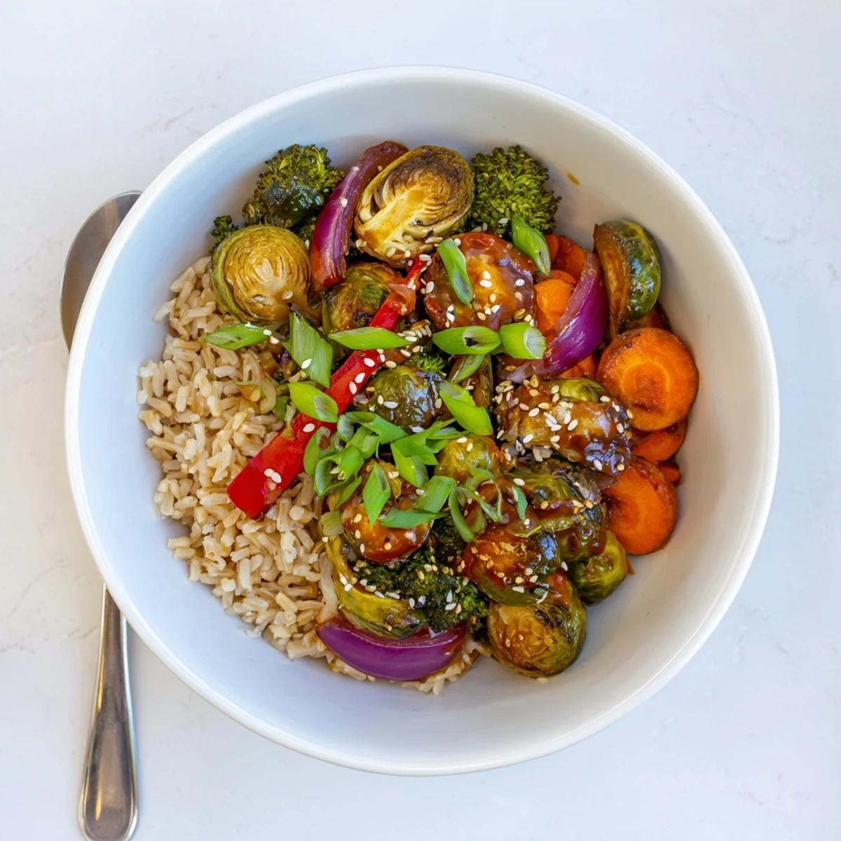 Caramelized Brussels sprout veggie bowl drizzled in spicy garlic sauce served steaming hot