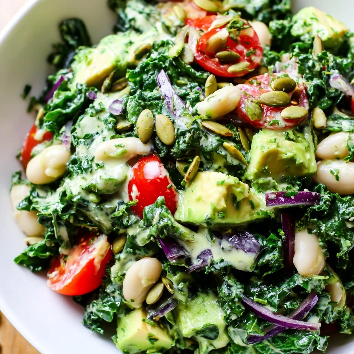 Creamy avocado white bean kale salad bowl topped with bright lemon zest dressing