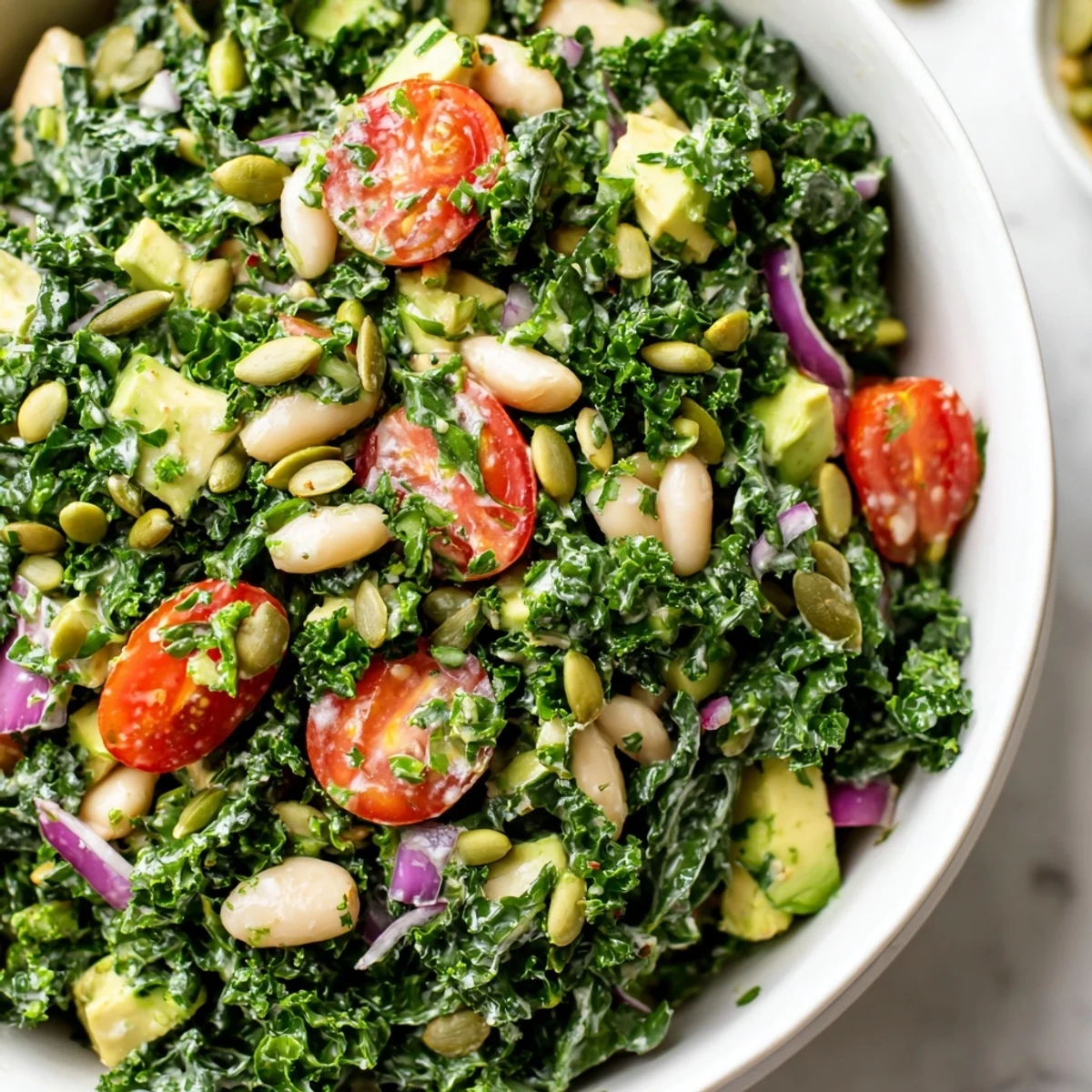 Massaged kale white bean and avocado salad bowl finished with fresh lemon zest