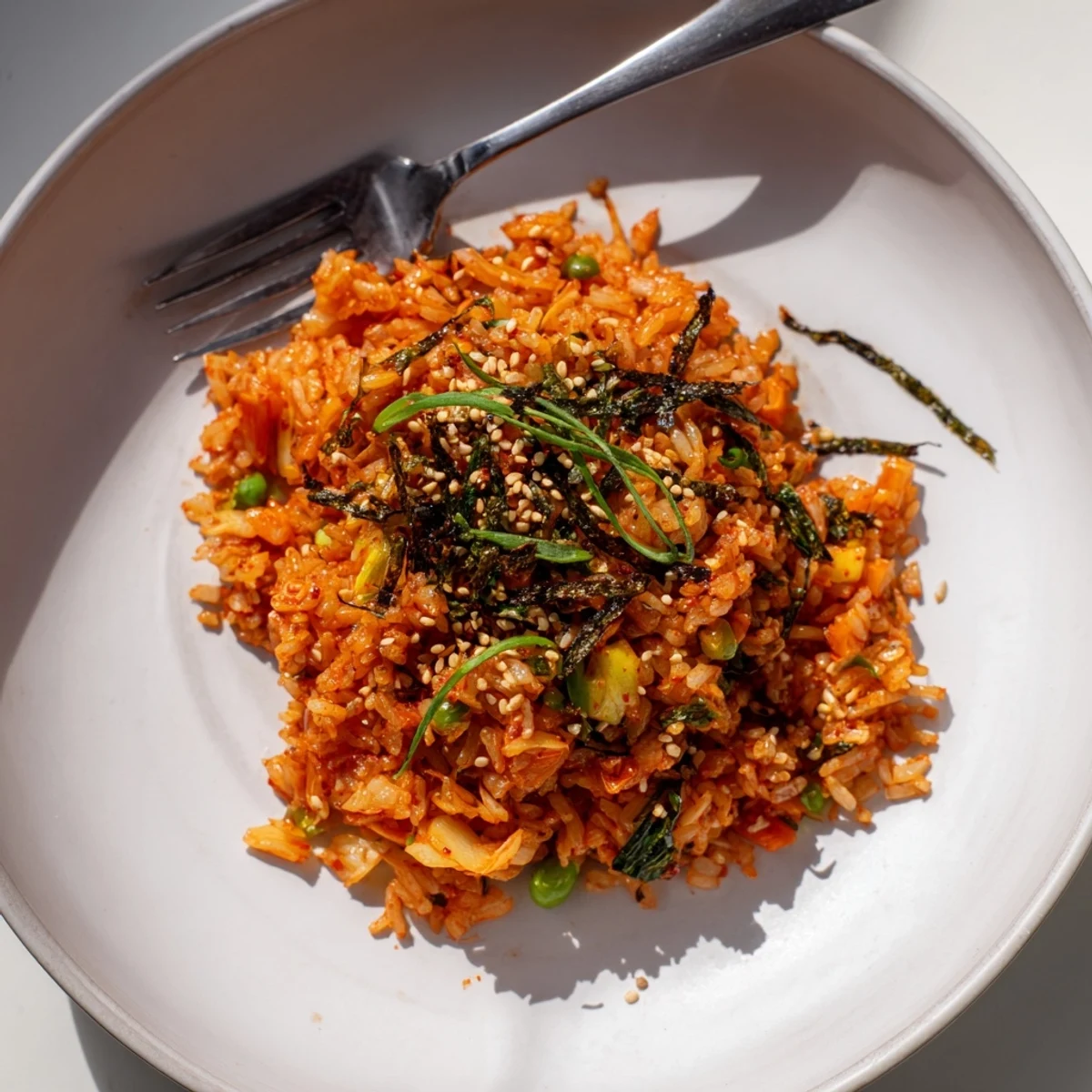 A close-up of kimchi garlic fried rice topped with crunchy golden scallions and sesame seeds