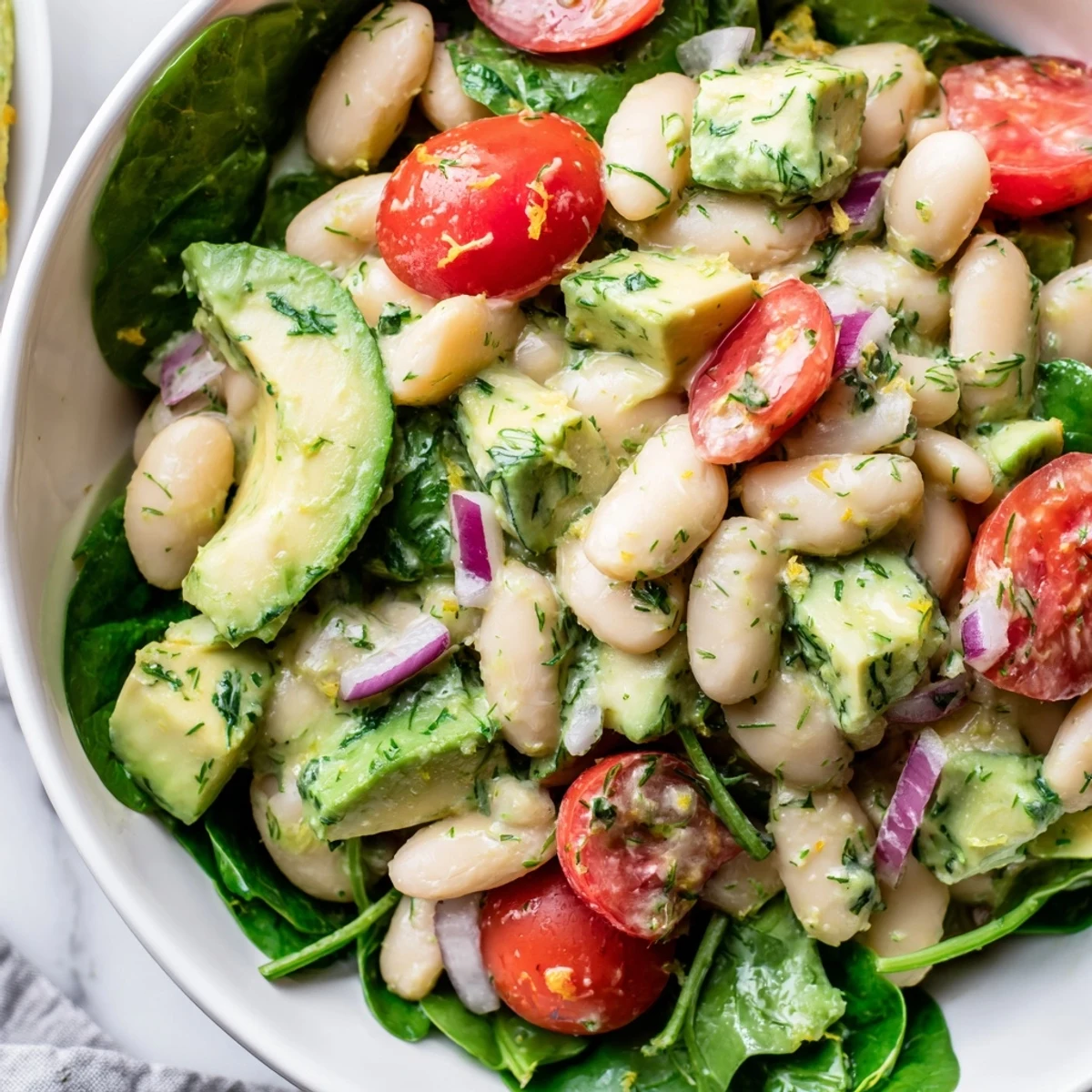 Creamy avocado white bean salad topped with cherry tomatoes and fresh dill