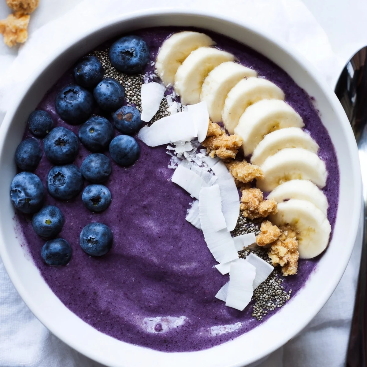 Creamy blueberry banana cashew smoothie bowl topped with coconut flakes and fresh berries