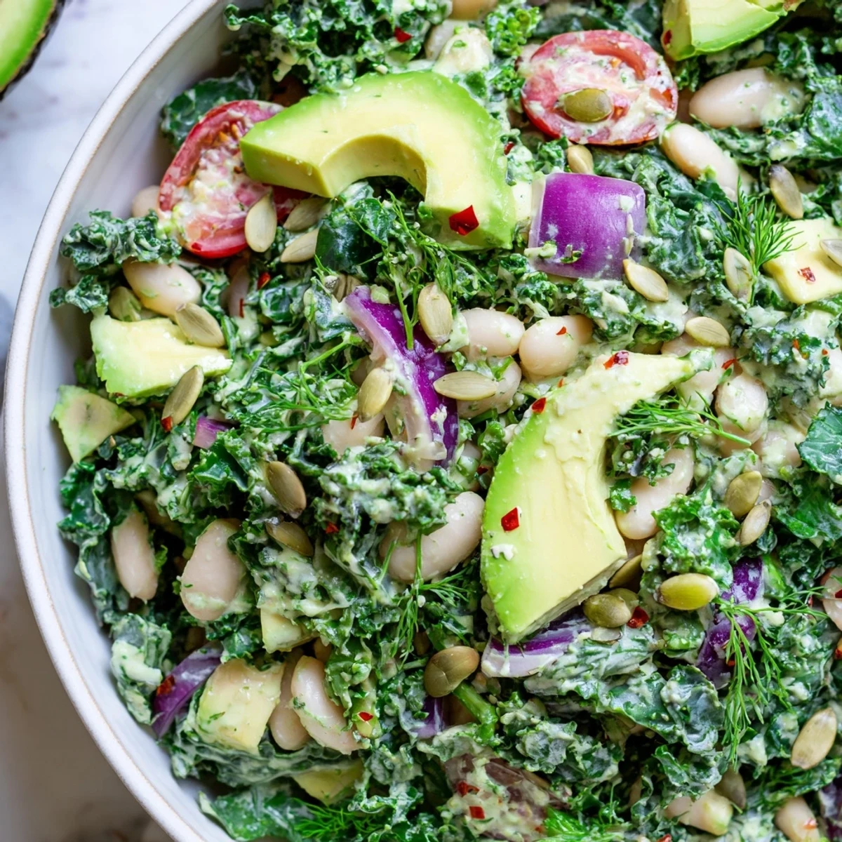 Vibrant avocado white bean kale salad bowl with cherry tomatoes and creamy herb dressing