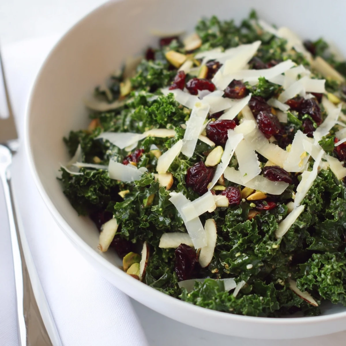 Colorful kale apple pistachio salad bowl drizzled with bright citrus dressing