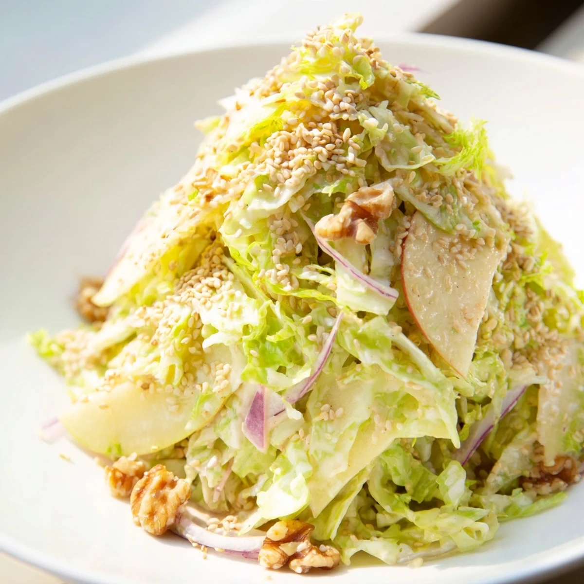 Colorful cabbage apple walnut salad bowl tossed in creamy sesame dressing