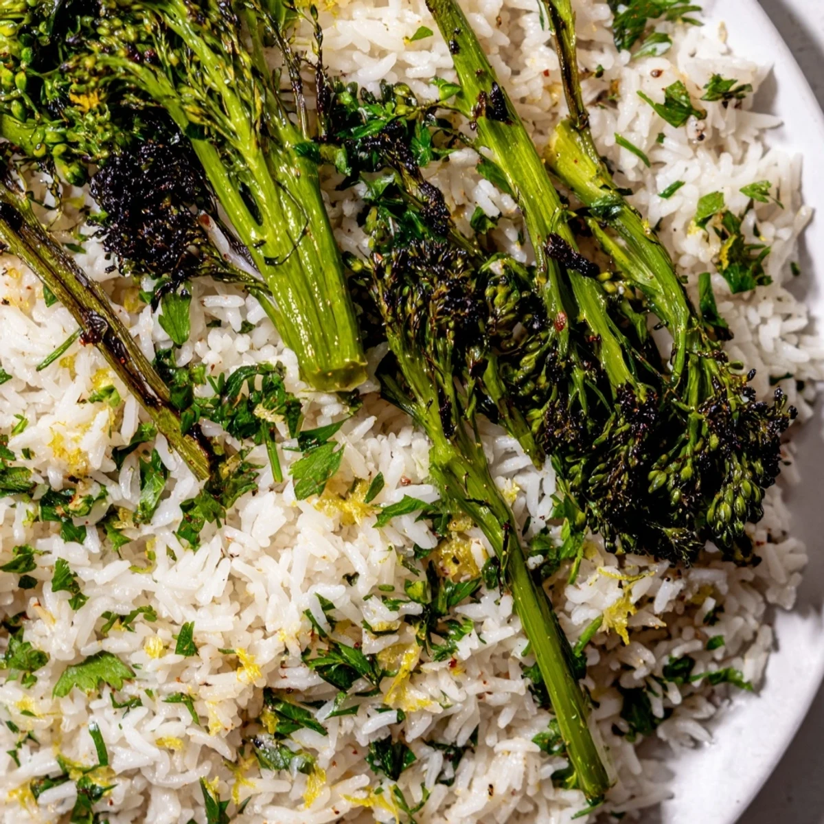 Bright green charred broccolini nestled beside fragrant garlic herb jasmine rice with fresh herbs