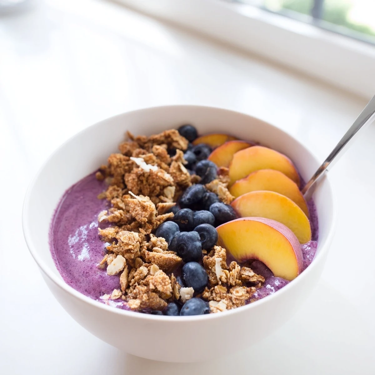Close-up of nutritious breakfast bowl featuring creamy fruit smoothie, crunchy granola, and almond slices.