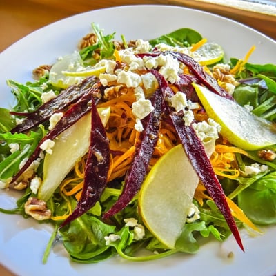 Vibrant Root Pear Greens salad with shredded carrots, sliced pears, and a tangy vinaigrette.
