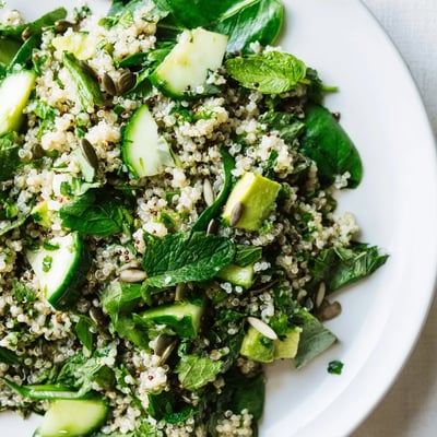 Green onion and cucumber garnish this vibrant Emerald Quinoa, with diced avocado and toasted pumpkin seeds adding texture.