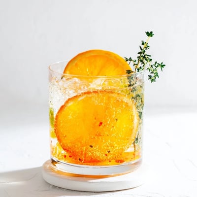 Bright citrus slices and aromatic rosemary top a sparkling pitcher of Citrus Evergreen Mix mocktail.