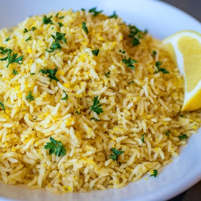 Vegan gluten-free lemon turmeric basmati rice served with smoky charred broccolini and lemon wedges for a light dinner side.
