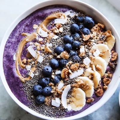 The creamy Blueberry Almond Butter Smoothie Bowl with Chia Crunch is garnished with sliced almonds and coconut for a delightful breakfast.