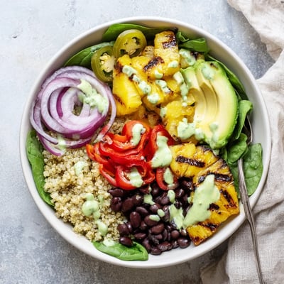 A close view of the Charred Pineapple Jalapeño Grain Bowl shows quinoa, black beans, cherry tomatoes, and zesty cilantro lime dressing.
