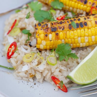 Vibrant Coconut Lime Brown Rice Dish with Charred Corn served with lime wedges.